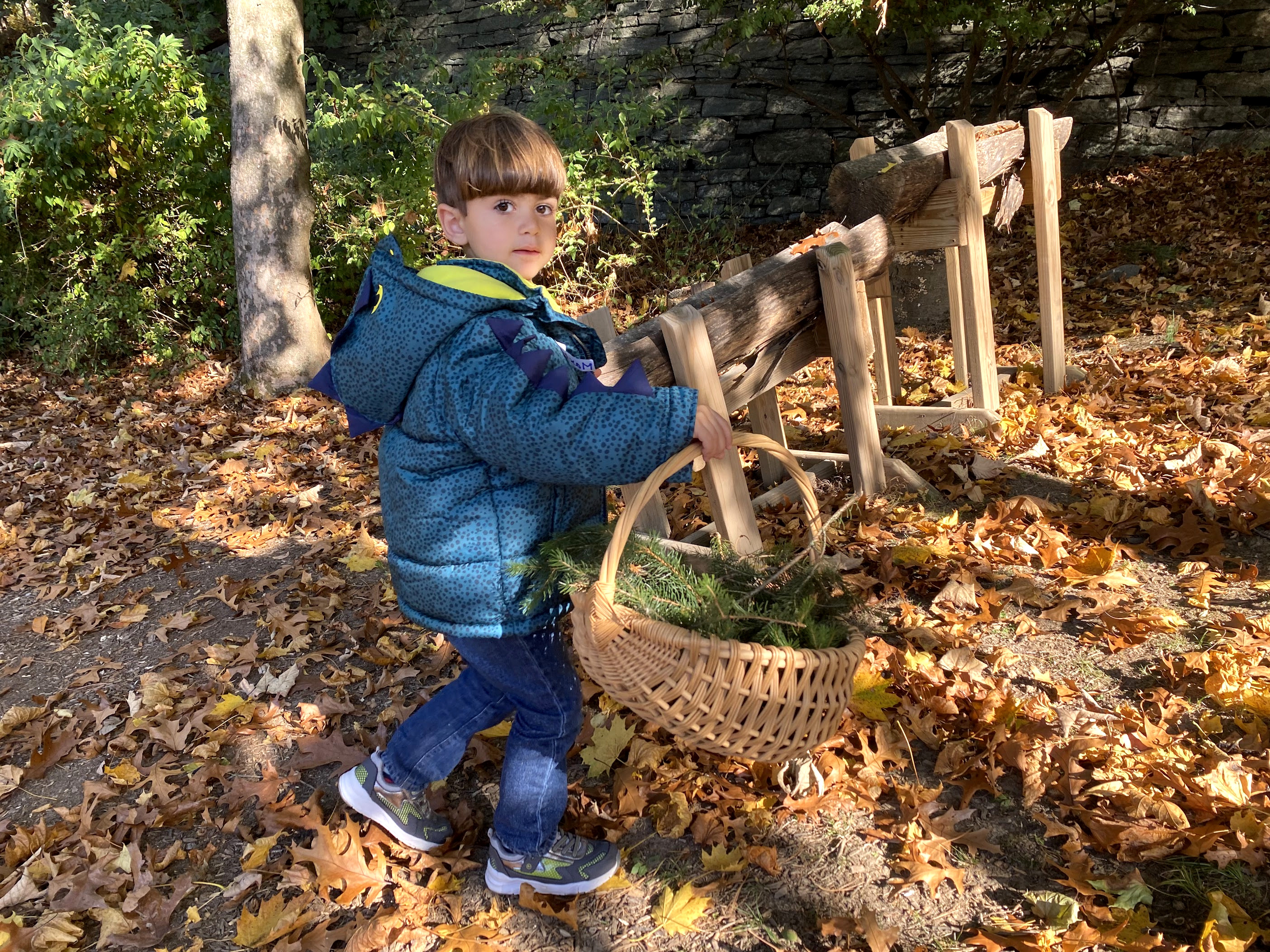 A toddler exploring a basket of natural materials outdoors